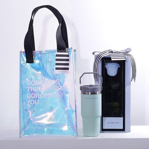 A chic and modern gift set with a blue and iridescent theme. The hamper includes a large, transparent holographic tote bag with black handles and the text "GORGEOUS THINGS FOR GORGEOUS YOU." The bag also features a black-and-white striped tag. The set contains a tall, sky blue tumbler with a grey handle. The set also includes a matching sky blue box that showcases a single, beautifully preserved sky blue rose. This stylish and thoughtful hamper is a perfect gift for someone special.
