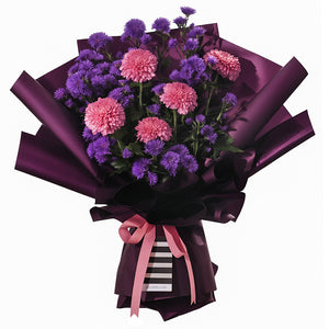 A striking bouquet featuring full pink chrysanthemums and delicate purple asters. It is elegantly wrapped in deep purple paper with a modern black and white striped accent at the base. The arrangement is tied with a pink ribbon bow, creating a full, rounded shape. This sophisticated bouquet is perfect for birthdays, anniversaries, or as a thoughtful thank-you gesture.