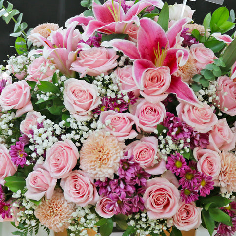 An opulent floral arrangement in a clear glass vase, featuring a magnificent mix of pink and white blooms. The bouquet includes elegant pink lilies, light pink roses, delicate baby's breath, and other pink and purple filler flowers, accented with lush eucalyptus leaves. A striped ribbon and a "Hello gorgeous" card are tied to the vase, with a small black tag at the top. This grand, luxurious display is perfect for celebrating monumental occasions.